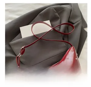 Detail of red faux leather shoulder bag with silver rivet studs on gray suit jacket