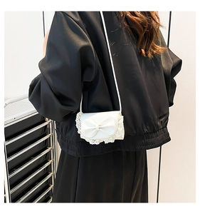 Close-up of a white mini crossbody bag featuring a large 3D bow and delicate lace trim