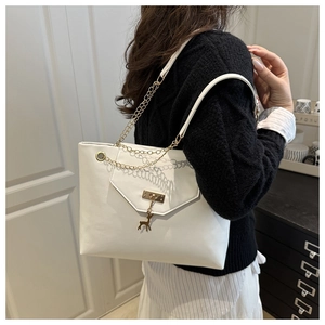 Detail of white PU leather tote bag featuring a gold chain strap and a deer pendant charm