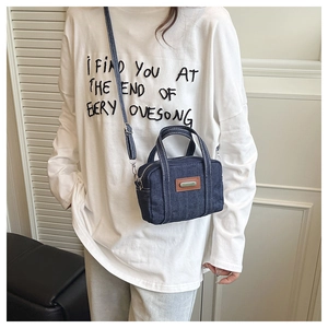 Detail of dark blue denim mini crossbody bag with leather patch and adjustable strap