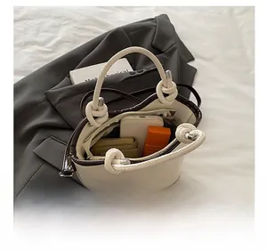 Detail of off-white bucket bag with knotted handle showing interior storage capacity