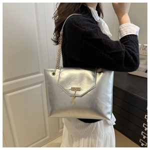 Detail of silver metallic tote bag with golden deer charm and chain shoulder strap