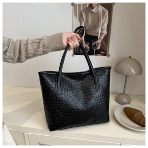 Close-up of black woven tote bag with intricate leather texture and round handles