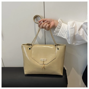 Close-up of beige patent leather bag with gold deer pendant and chain strap detail
