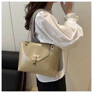 Detail of khaki glossy tote with silver deer pendant and chain strap on shoulder