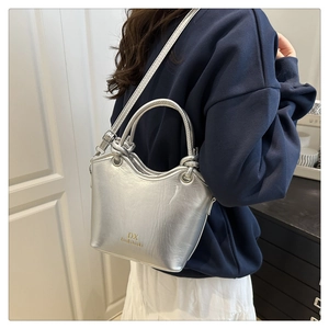 Close-up of metallic silver bucket bag with double handles and long shoulder strap