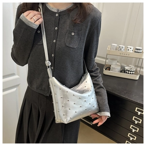 Detailed close-up of a silver rivet-studded shoulder bag with metallic finish and zipper