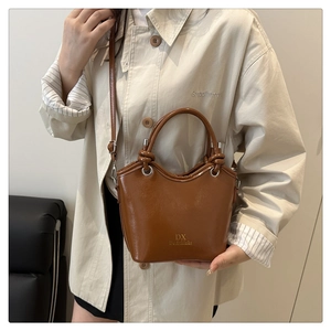 Detailed view of the brown glossy leather texture and embossed logo on the bucket bag