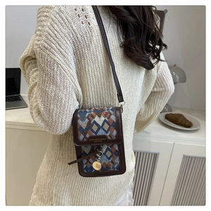 Detailed texture of woven plaid fabric with brown leather trim on a mini crossbody bag
