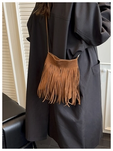 Close-up of brown suede shoulder bag with long bohemian fringes and slim strap