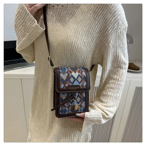Detail of vintage geometric woven crossbody bag with brown leather flap and metal charm