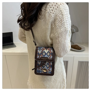 Detail of vintage crossbody phone bag with diamond weave pattern and brown leather trim