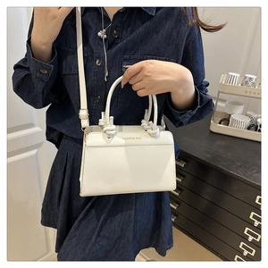 Detailed shot of white leather handbag with knotted handle and adjustable shoulder strap