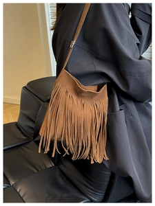 Detail shot of brown suede fringe shoulder bag with bohemian tassels and metal buckle