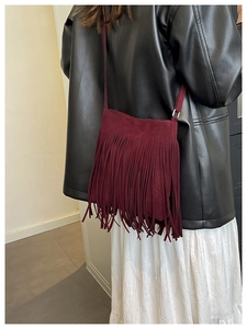 Détail du sac bandoulière en daim rouge vin avec de longues franges sur un mannequin