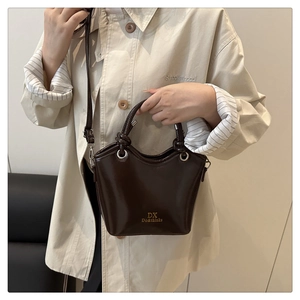 Close-up of brown leather bucket bag featuring a knotted handle and gold logo hardware