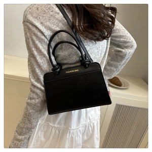 Detail of black leather crossbody bag with knot handle and golden fashion lettering