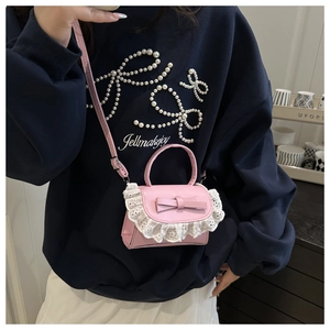 Close-up of pink crossbody bag featuring white lace trim and a delicate bow detail