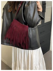 Detail of burgundy faux suede fringe crossbody bag with adjustable silver buckle strap