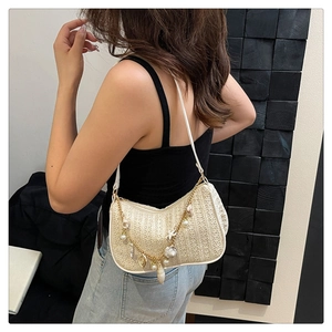 Detail of straw woven bag with decorative pearl shell chain and white leather shoulder strap