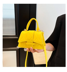 Detail of a bright yellow quilted felt mini bag held by hand to show compact size