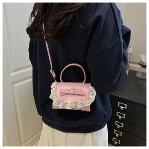 Detail of pink faux leather crossbody bag with 3D bow and delicate white lace embroidery