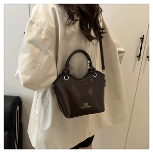 Detail of dark brown leather bucket bag showing glossy finish and gold logo lettering