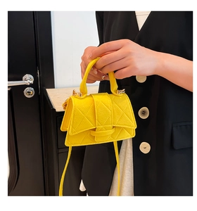 Detail of yellow quilted crossbody bag on model with elegant diamond stitch pattern