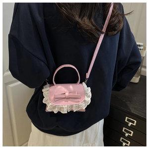 Detailed close-up of pink lace-edged crossbody bag with a cute bow on blue sweatshirt