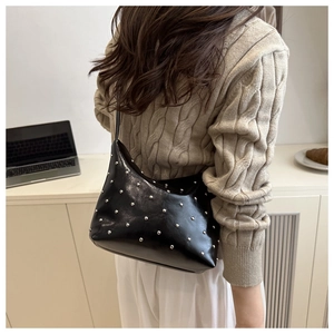 Detail of vintage black bucket bag with silver metal rivets and glossy leather texture
