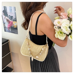 Close-up of straw woven baguette bag featuring pearl and shell metal chain detail