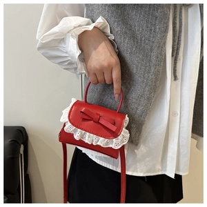 Close-up of a red mini handbag with white lace trim and a delicate ribbon bow detail