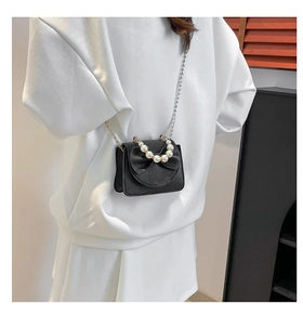 Close-up of black mini crossbody bag with pearl handle, bow decoration and gold chain