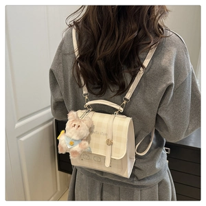 Close-up of beige checkered mini backpack with teddy bear charm and cute graphic design