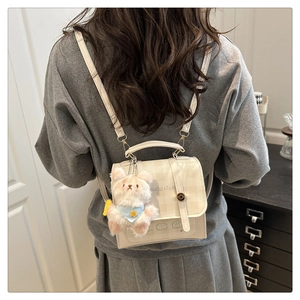 Detail of a chic cream checkered backpack with a cute bear charm and animal illustration