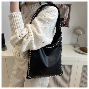 Detail of black leather tote bag featuring silver studs on the strap and edge