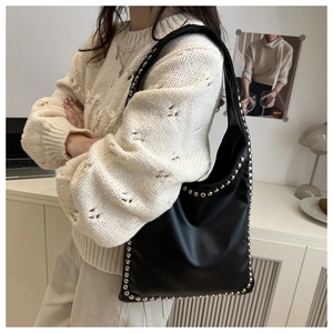 Detail of black matte tote bag featuring silver rivet trim on wide shoulder strap