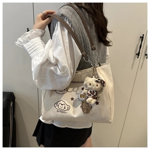 Canvas tote bag with cute cat graphics, brown leather straps, and plush pendant detail