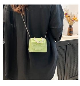 Detail of lime green mini bag with bow accent, pearl handle and golden chain strap