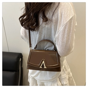 Detailed side view of a brown vintage leather crossbody bag with a gold V-shaped buckle