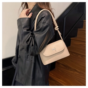 Détail d'un sac à bandoulière beige chic avec nœud argenté et lanière nouée