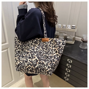 Detailed close-up of large leopard print tote bag with front pocket and leather label