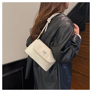 Detail of off-white shoulder bag with silver bow ornament and knotted rope strap
