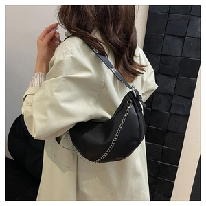 Detail of black crescent shoulder bag with silver chain and wide grommet strap