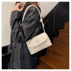 Détail du sac bandoulière crème avec nœud en métal argenté et bandoulière nouée