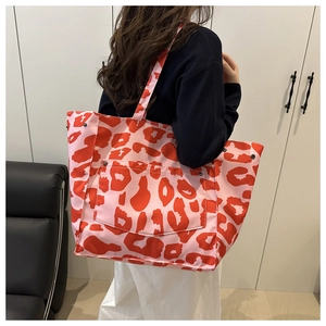 Détail du sac cabas en toile rose à imprimé léopard rouge et boutons-pression latéraux