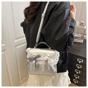 Silver metallic crossbody bag with white lace trim and gingham bow detail on model