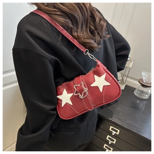 Detail of red pebbled leather underarm bag featuring white star patches and star buckle