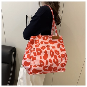 Detail of pink leopard print nylon tote bag featuring front pocket and leather patch