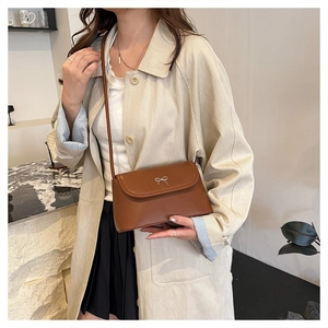Fashionable brown PU leather crossbody bag with silver bow detail shown on a model